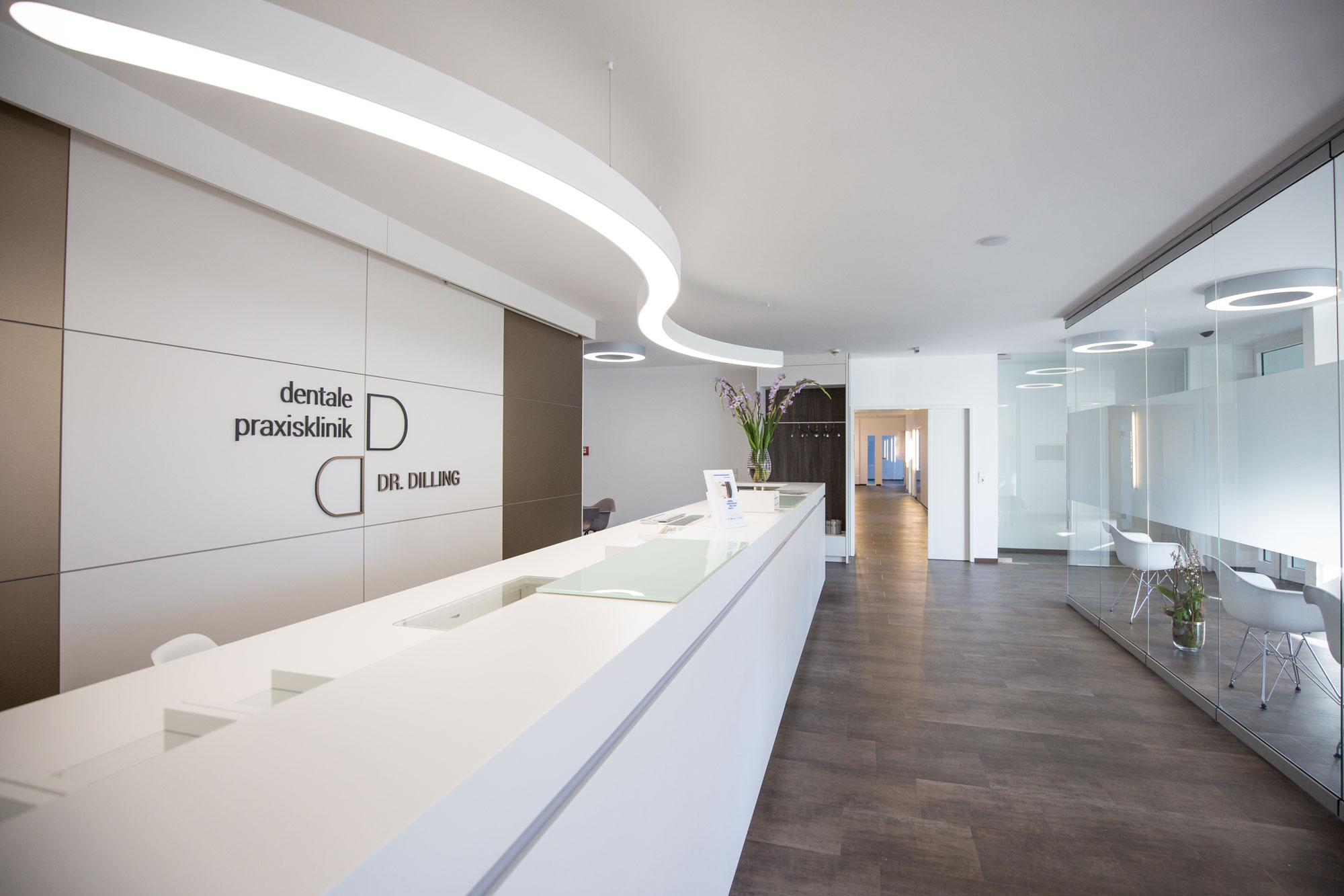 A large, white ceiling light provides bright and inviting lighting in the reception area of a modern doctor's office.